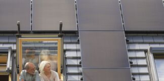 Foto zeigt ein Paar am Dachfenster mit Blick auf die PV-Anlage